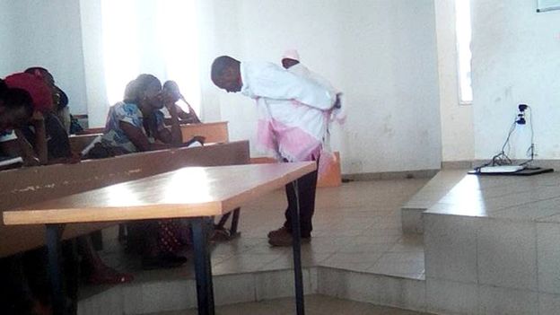 Professor Honore Kahi carries baby on the back while lecturing